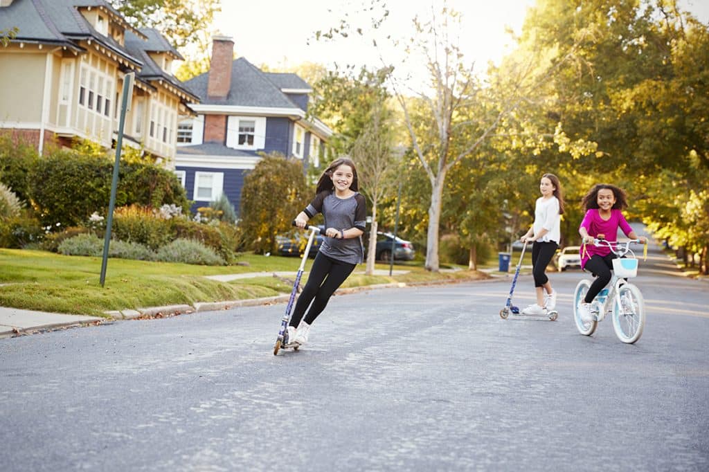 Defunding the police could make children less safe, like these girls playing in street on scooters and bike